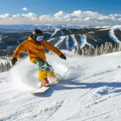 Snowboardzista w żółtej kurtce i zielonych spodniach jeździ po ośnieżonym stoku.