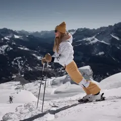 Kobieta na nartach z kijami na tle górskiego krajobrazu.