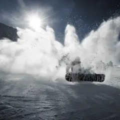 Snowboardzista wykonujący obrót 360 stopni, wzbijając chmurę śniegu.