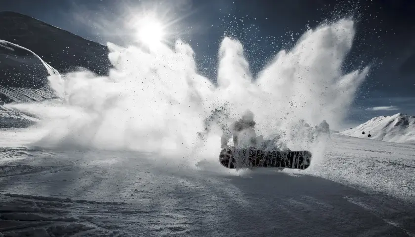 Snowboardzista wykonujący obrót 360 stopni, wzbijając chmurę śniegu.